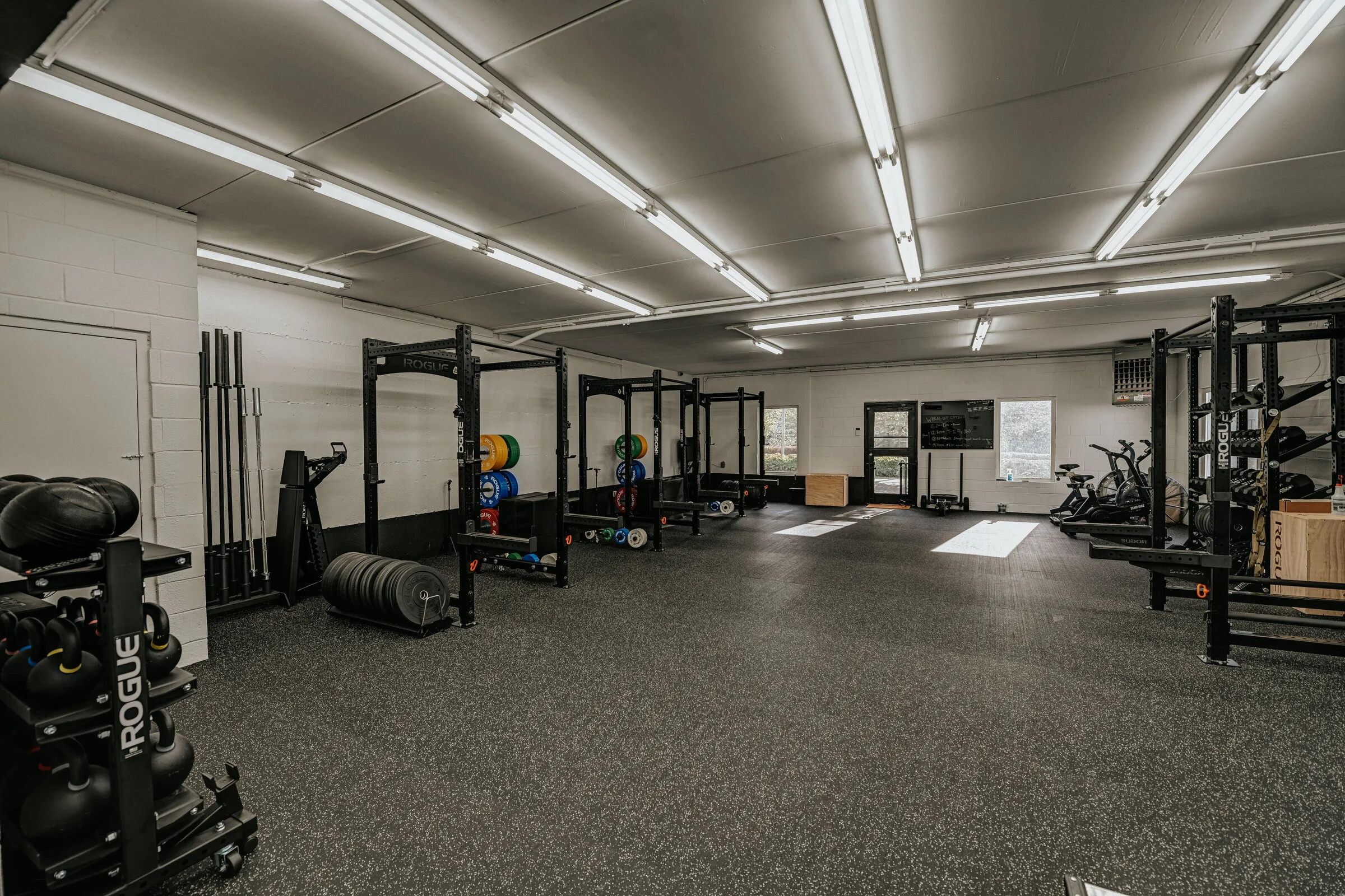 Racks, kettlebells and conditioning equipment across the gym floor